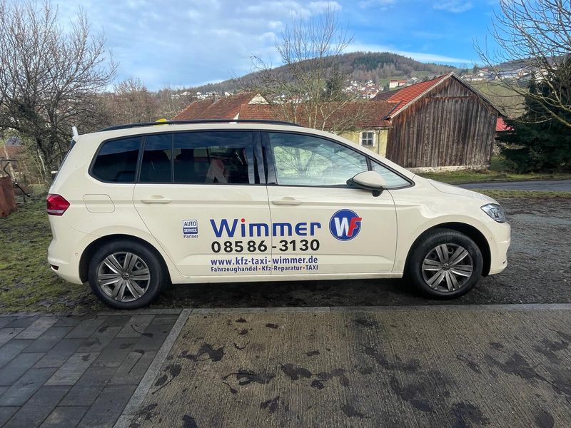 Taxi von Wimmer mit Dachzeichen und Beschriftung, davor die Hügel rund um Hauzenberg