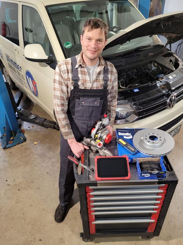 Fritz Wimmer jun. in der Werkstatt mit einem ausgebauten Turbolader, daneben neue Bremsscheiben auf dem Werkzeugwagen